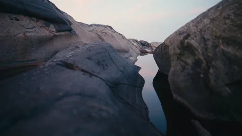 Camera Descending Toward a Calm Tide Pool Between Granite Rocks Stock Footage 341071359