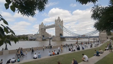 Camera dollies forwards towards crowds sitting on grass by Tower Bridge 動画素材 93787695