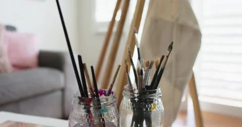 Camera dolly is moving forward, bringing two glass jars of paintbrushes near Stock-Footage 337160528