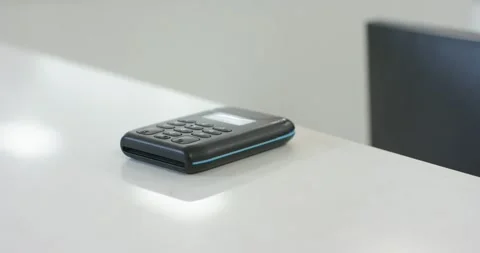 Camera is dollying in, highlighting black keypad device sitting on white desk Stock Footage 339558713