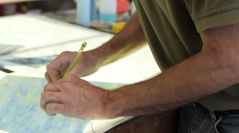 Camera dollys left past man cutting stained glass Stock Footage 33063889