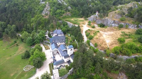 A camera drone flies ahead and above Cetinje Monastery and surrounding mountains Stock Footage 249420654