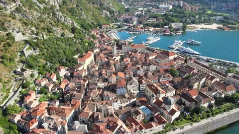 A camera drone flies ahead and above Kotor Old Town and the marina Stock Footage 249421038