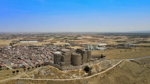 A camera drone flies ahead over iconic Consuegra Castle and windmills Stock Footage 202073013