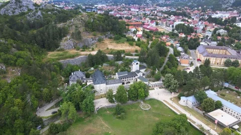 A camera drone flies ahead over Cetinje Monastery Stock Footage 249420229