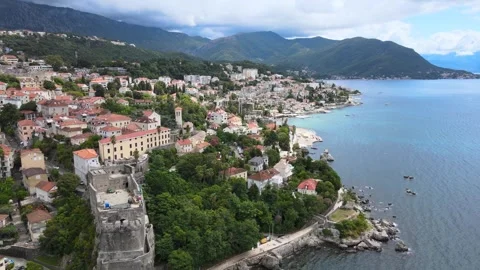 A camera drone flies ahead over a coastline of Herceg Novi and the Old Town Stock Footage 249422314