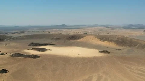 Camera drone flies ahead over a crater in the Harrat Kishb volcanic field Stock Footage 287481393