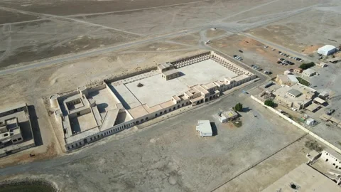 A camera drone flies around Aqeer (Al Uqayr) Castle Stock Footage 220083919