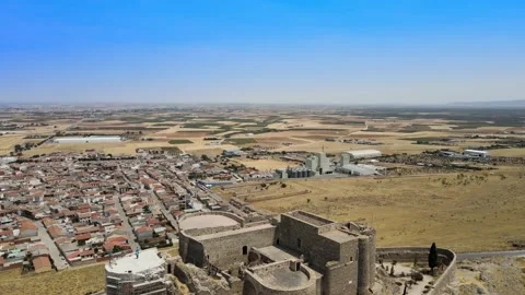 A camera drone flies backward over iconic Consuegra Castle and windmills Stock Footage 202072979