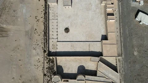 A camera drone flies backward over Aqeer (Al Uqayr) Castle, Saudi Arabia Stock Footage 220083883