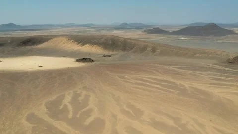 Camera drone flies backwards over a crater in the Harrat Kishb volcanic field Stock Footage 287481439