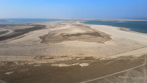 A camera drone flies forward over the desert and sea near Al Uqayr Stock Footage 220084663