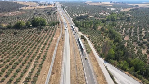 A camera drone flies over a highway with trucks transporting wind turbine blades Stock Footage 202073308