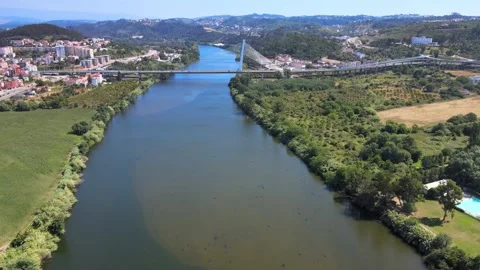 A camera drone flies over Mondego River towards the Rainha Santa Isabel Bridge Stock Footage 202024377