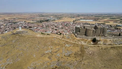 A camera drone flies sidewise over iconic Consuegra Castle and windmills Stock Footage 202072942