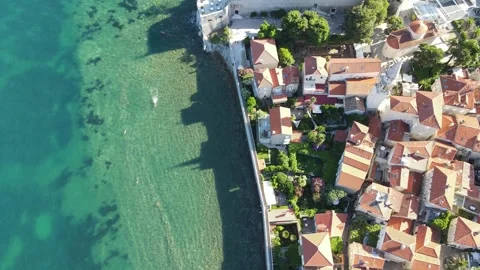 A camera drone flies sidewise over Budva Old Town and Ričardova Glava beach Stock Footage 249418888