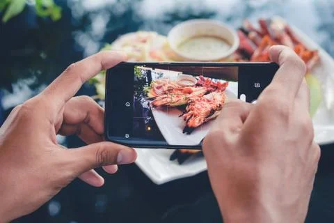 Camera eats first concept: man taking pictures food on the table with smartphone Stock Photos