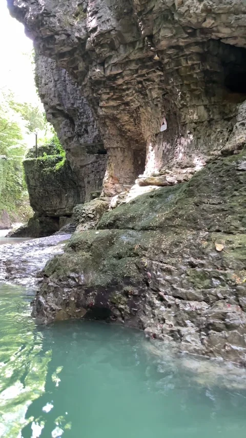 Camera explores a rugged limestone cave beside turquoise river water, showi.. Stock Footage 341257693