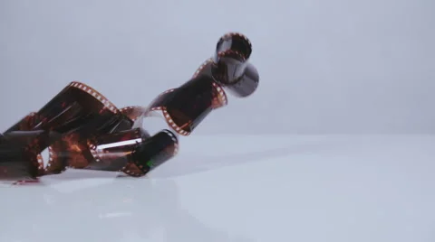 Camera film negative falling on white surface slow motion Stock Footage 58761475