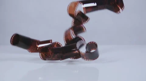 Camera film negative falling on white surface slow motion Stock Footage 58761478