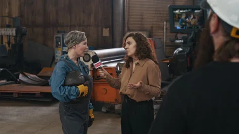 Camera Filming Young Reporter Interviewing Mature Female Welder in Repair Shop Stock Footage 320702219