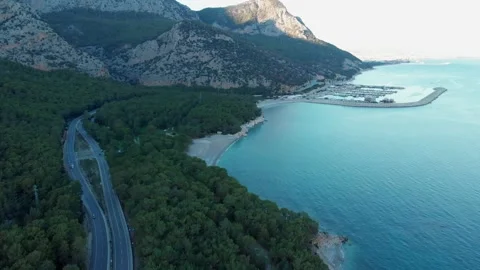 The camera flies along the coast, over the road on which cars are traveling. Video stock 227574386