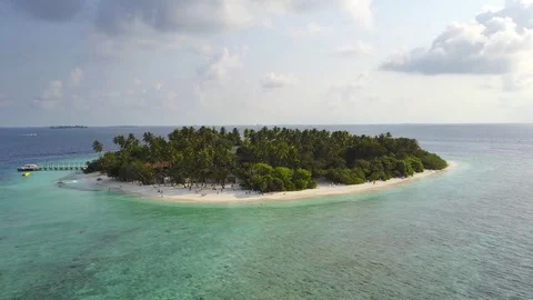 The camera flies around the small round tropical atoll island resort hotel with Stock Footage 77549179