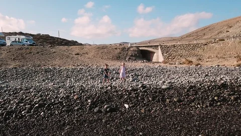 Camera flies away from two kids standing at a shore and throwing pebbles into Stock Footage 95898204