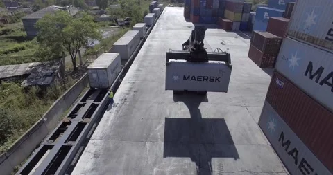 The camera flies behind a loaded container with a reachstacker. Stock Footage 145702594