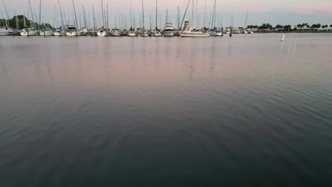 Camera flies low over water towards a sailboat and marina Stock Footage 337072727