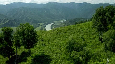 The camera flies out from behind the hill to a beautiful valley with a river. Stock Footage 168434083