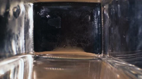 The camera flies out of the neck of a square glass bottle Stock Footage 142932358