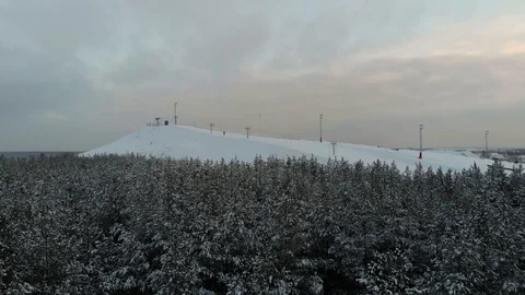 The camera flies over the forest towards the ski resort. Aerial view winter Stock Footage 99566398