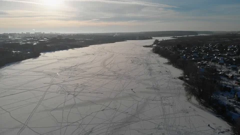 The camera flies over the frozen river with fishermen in the winter. Aerial view Stock Footage 99170608