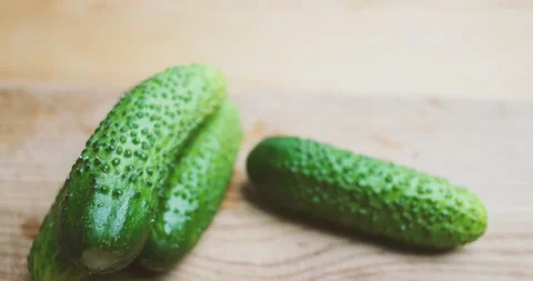 Camera flies over green cucumbers lying on a wooden cutting board. Close-up. Stock Footage 202162001