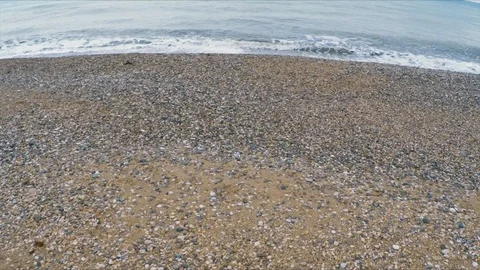 The camera flies over the pebble beach to the sea Stock Footage 91396368