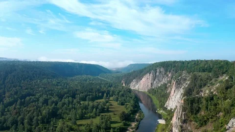 The camera flies over the river at the foot of a mountainous rocky ridge. 스톡 동영상 114871776