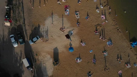 The camera flies parallel to the sand on the beach with the resting people. Stock Footage 91521044