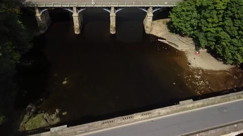 Camera flies past road and former rail bridges, river, UK Stock Footage 159706482