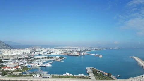 Camera flies towards a small sea cargo port where a cargo ship is being loaded. Stock Footage 233156117