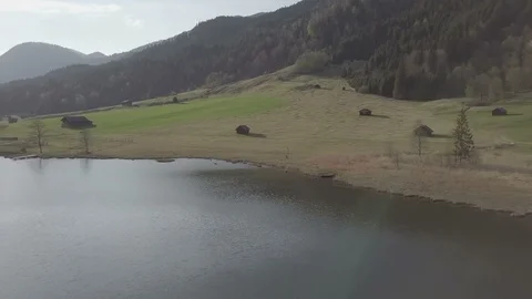 Camera flight above the lake and the green slope in the mountains sunset time Stock Footage 89761196