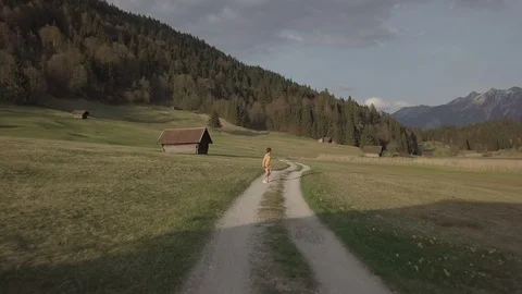Camera flight along the road on the mountains with running person on it Stock Footage 89789396
