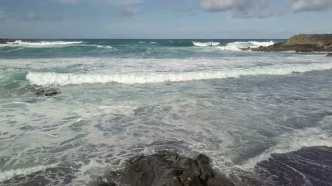 Camera flight in front of the ocean wave with the girl observing the ocean view Stock Footage 85085316
