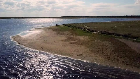 Camera flight over a lake and headland with birds taking off 動画素材 234992047
