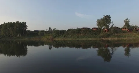 Camera flight over the lake, clear like a mirror. It reflects the trees on the Stock Footage 79407712