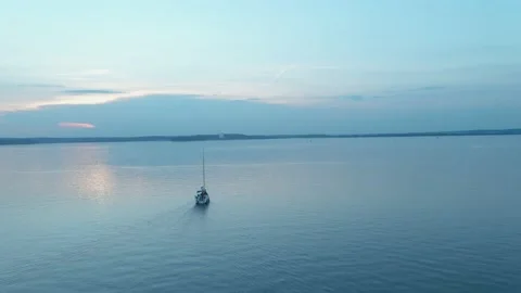 Camera flight over a sailboat on a large cinematic blue lake at a pink sunset Vídeo Stock 166545947