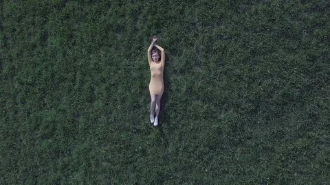 Camera flight zoom out top down view above the girl on the green lawn Video stock 89746453