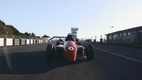 Camera fly over RED RACE CAR into the COCKPIT. Empty circuit on a sunny day Stock Footage 127404367