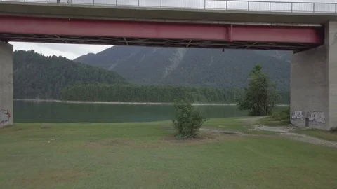 Camera fly under the bridge towards the mountains panorama view - Aerial Stock Footage 83737405