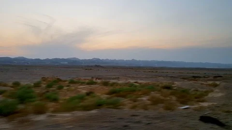 Camera flying along the green desert. Sunset, pink sky, mountains in blue smoke. Stock Footage 128548512